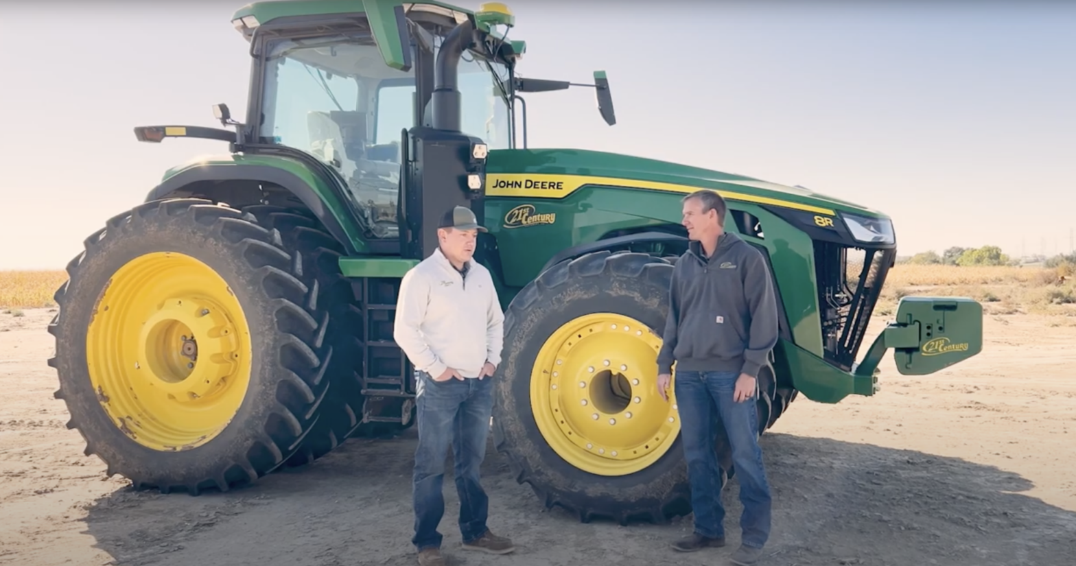 Mike Wemhoff and Hank Jackson have a conversation next to a John Deere tractor.